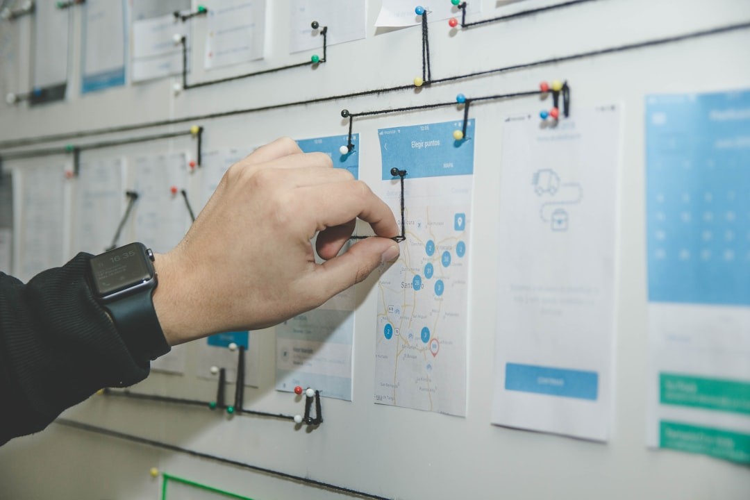 Person adjusting a string connection on a map pinned to a planning board, wearing a smartwatch.