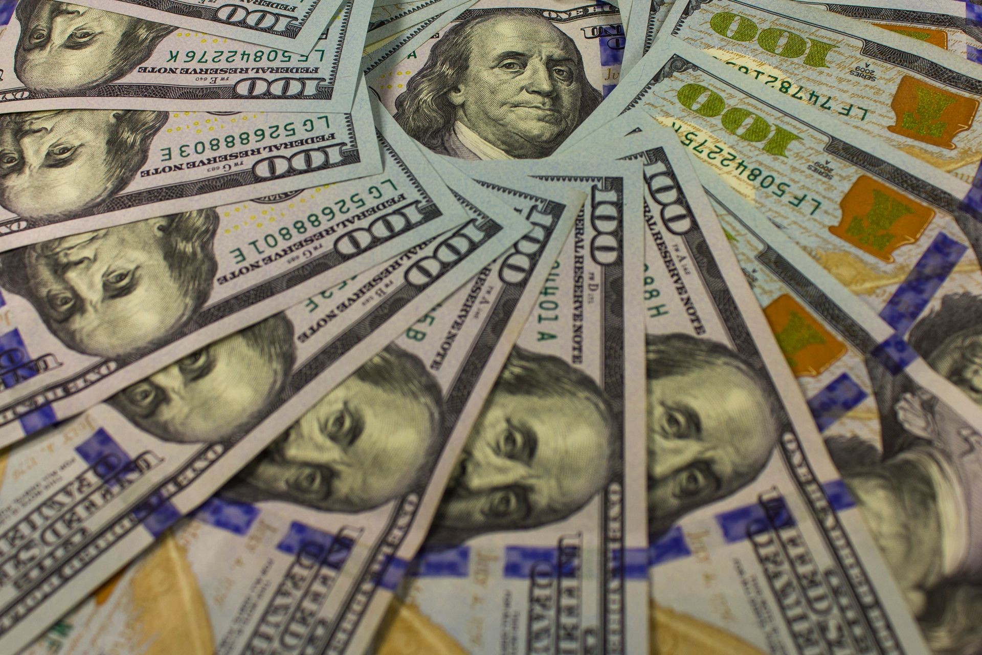 Banknotes worth 100 US dollars spread around portrait of President Franklin.